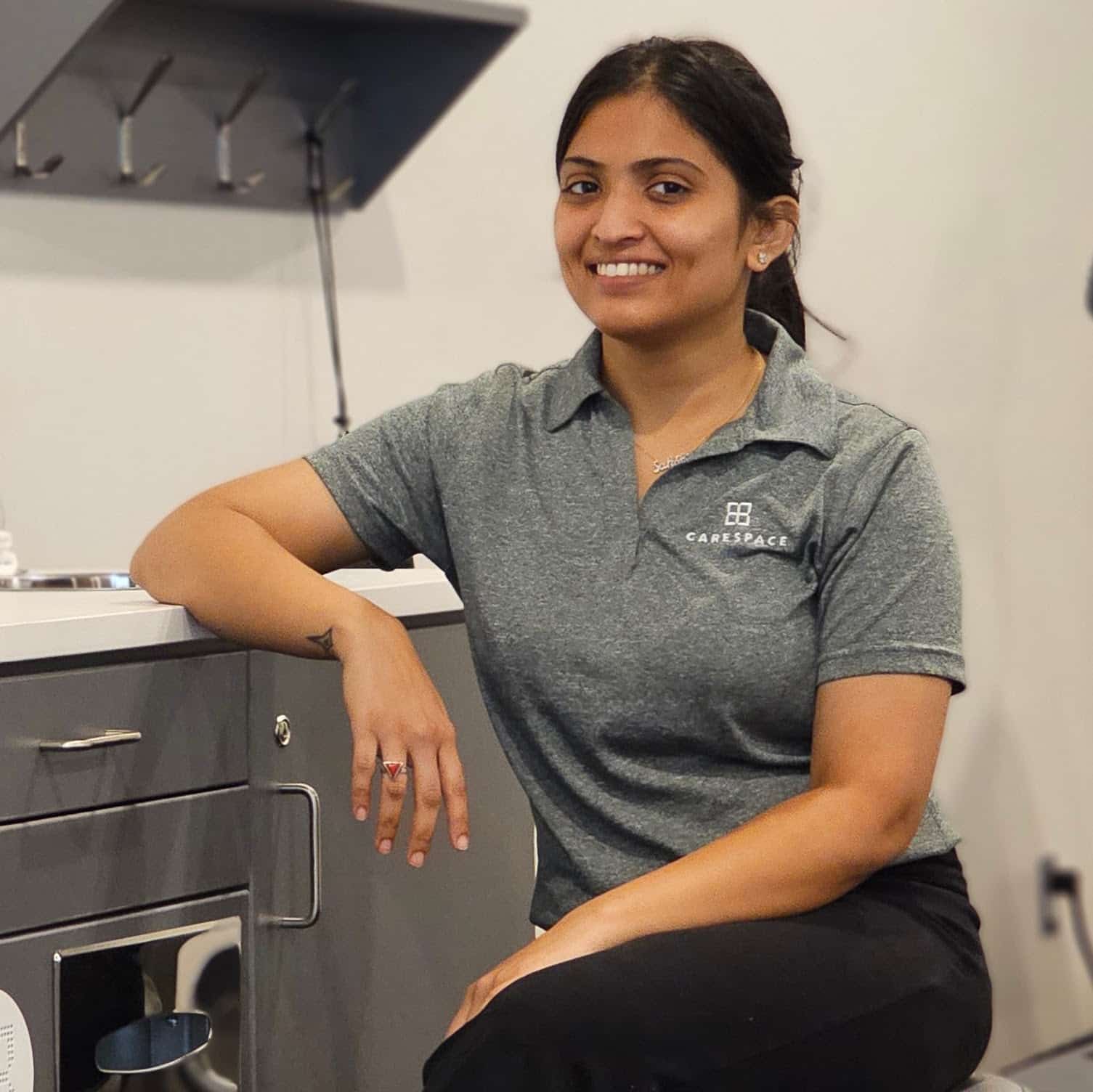 female Kitchener pelvic physiotherapist sitting at workstation in clinic with elbow on service cart