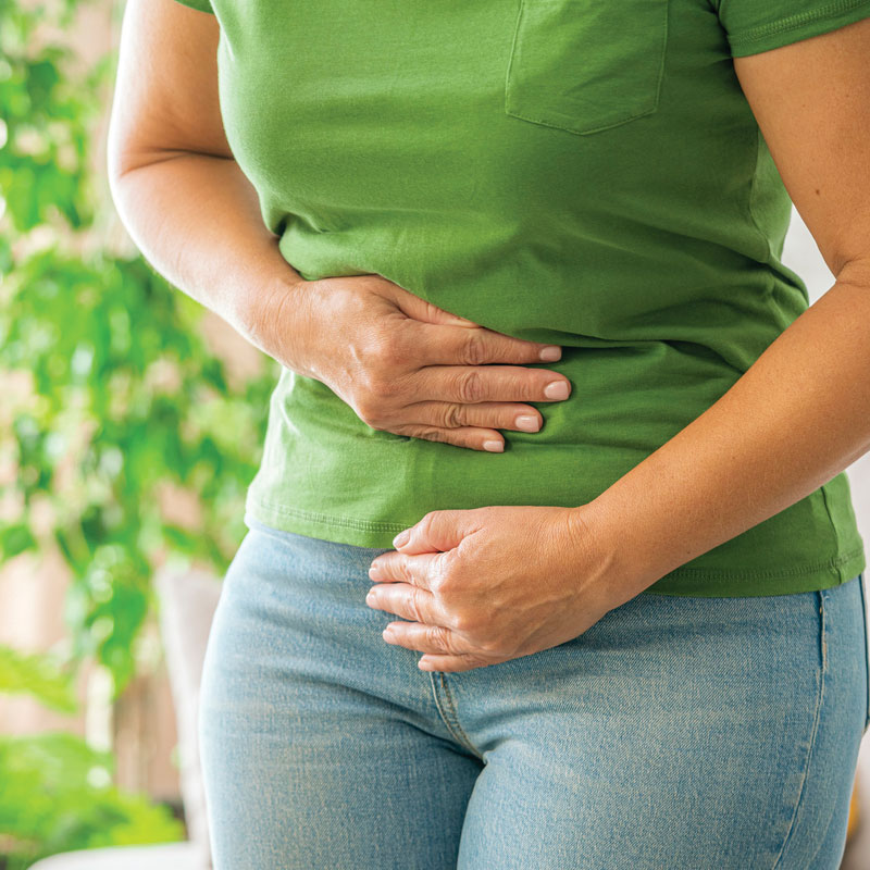 woman holding her stomach in pain with gas and bloating